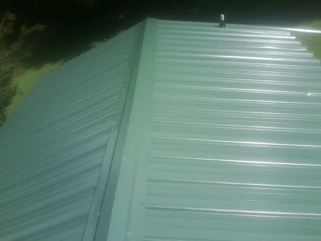New green metal panels meeting at the ridge of a roof — Flat Roof Repair work by our crew in Old Westbury