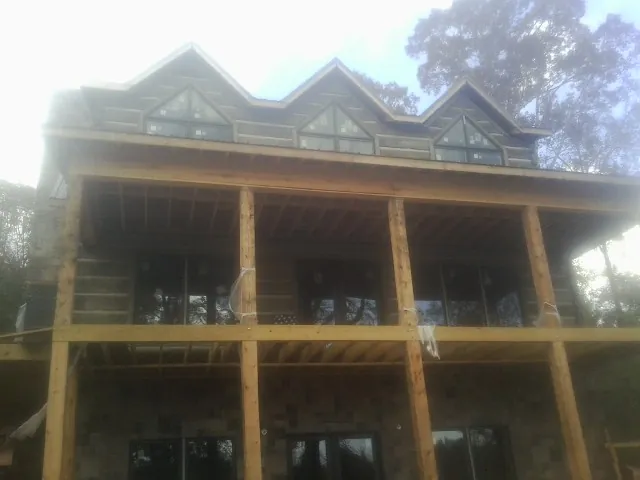 Dormers and porch framing on a large log home under construction — Roof Coating work by our crew in Old Westbury