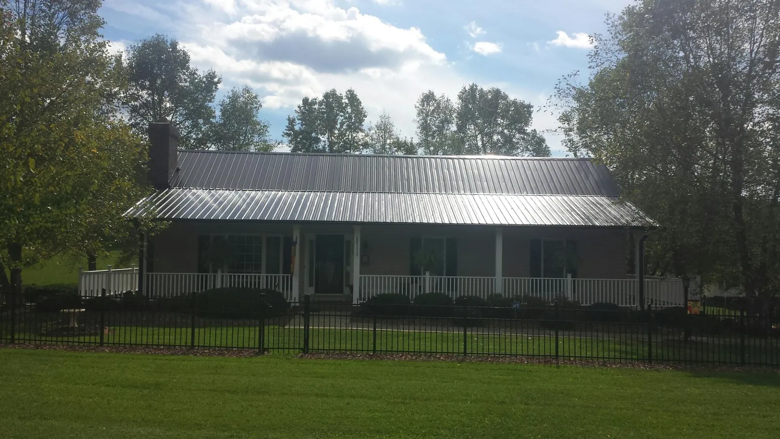 Gray metal roof on a brick ranch with a full width front porch — Gutter Guard Installation work by our crew in Old Westbury