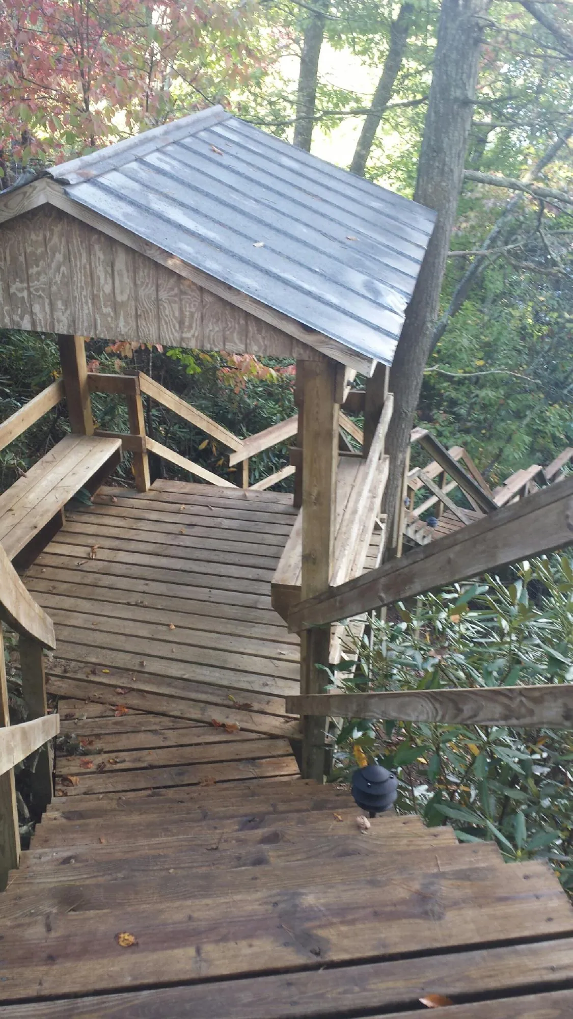 Metal roofed shelter over wooden steps on a wooded walkway — Skylight Repair & Installation work by our crew in Old Westbury