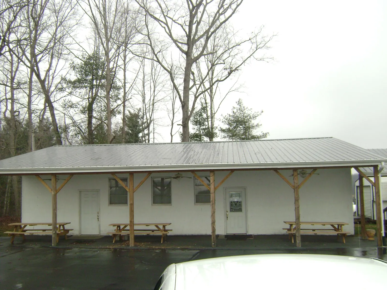 Gray metal roof over a block building with a timber post porch in Old Westbury